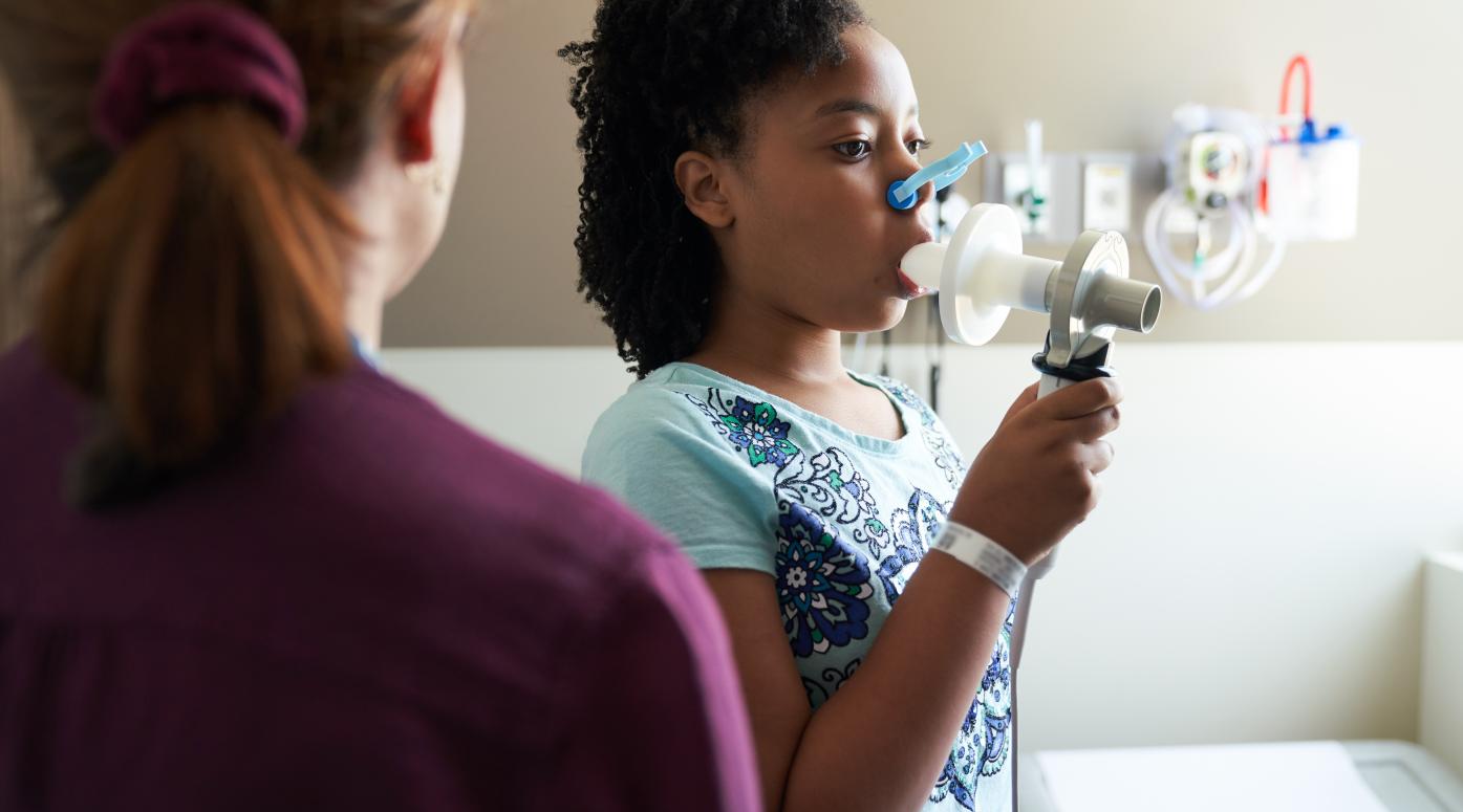 Young girl blowing into an asthma machine